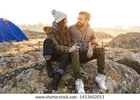 Photo of happy young loving couple outside with tent in free alternative vacation camping over mountains.