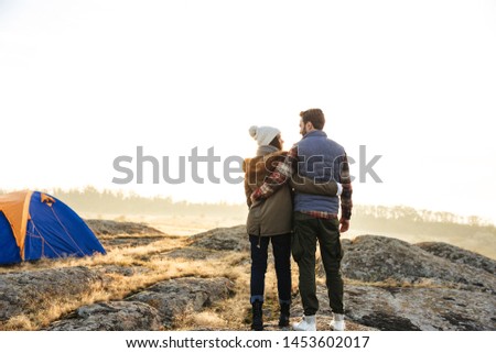 Photo of happy young loving couple outside with tent in free alternative vacation camping over mountains.