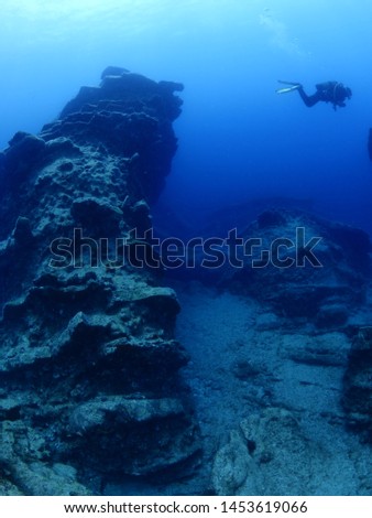 scuba divers underwater exploring and siscovering the strange shape rocks underwater