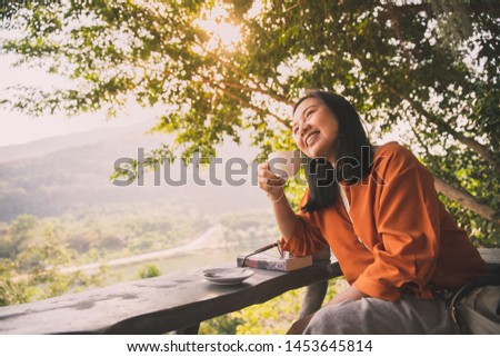 Cheerful woman relax drinking tea or coffee in morning with sunshine through the tree background, freedom lifestyle concept Royalty-Free Stock Photo #1453645814