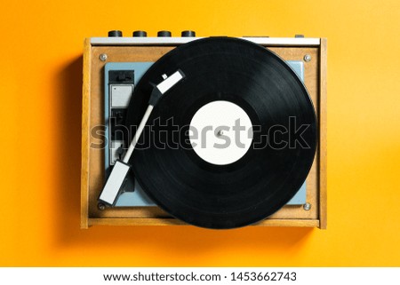 vintage turntable vinyl record player on orange background. retro sound technology to play music Royalty-Free Stock Photo #1453662743