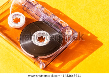 transparent audio cassette tape on orange background. retro music magnetic technology