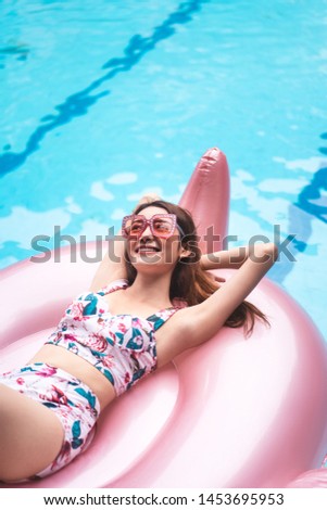 Vacation smile asian young woman arm up relax on pink flamingo inflatable in pool. 