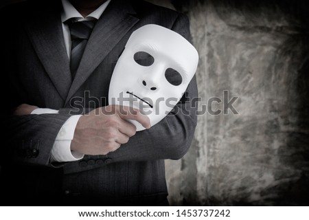 Businessman holding white mask in his hand dishonest cheating agreement.Faking and betray business partnership concept Royalty-Free Stock Photo #1453737242