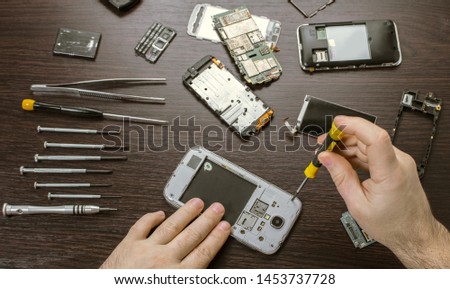 mobile phone repair, hands closeup on a wooden table