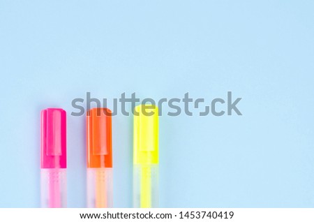 Three neon markers on a blue background. 