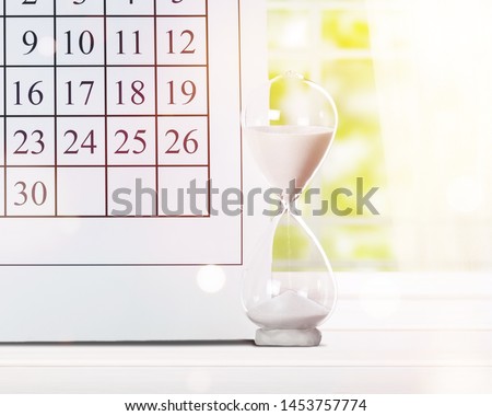Hour glass and calendar concept for time slipping away for important appointment date, schedule and deadline
    
    - Image