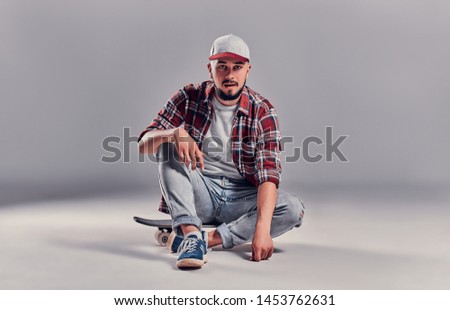 Teenage skater boy sitting on a longboard isolated on gray background.