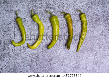 A few sharp green peppers on a concrete background. Horizontal orientation.
