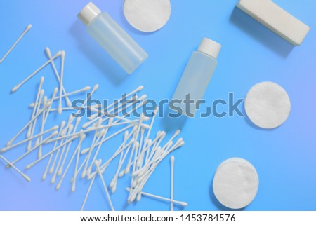 Cosmetic bottles, ear sticks and cotton swabs on blue violet background. The concept of makeup removal and skin care. Space for text, design