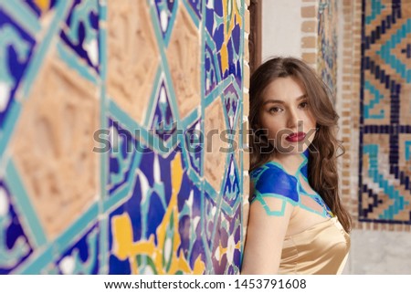 On the streets in Tbilisi in Georgia, public places. Brunette girl posing on the background of a wall with blue mosaic.