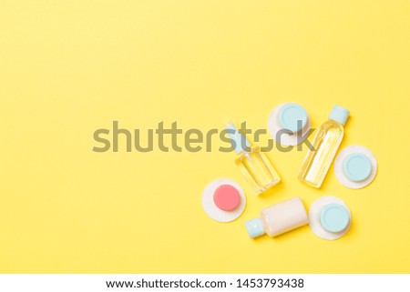 Set of travel size cosmetic bottles on yellow background. Flat lay of cream jars. Top view of bodycare style concept.