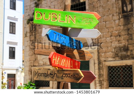 Tourism and travel concept. Colorful wooden road sign pointing directions and distances to different cities and countries - Havana, Dublin,  Costa Rica, Marrakesh for tourists