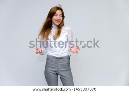 Portrait of a young beautiful brunette girl with beautiful long hair on a white background in a white jacket and gray pants. Right in front of the camera, smiling, showing emotions in various poses.