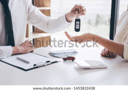 Car rent agent manager holding key of new car giving to woman client after signing good deal agreement contract, renting considering vehicle.
