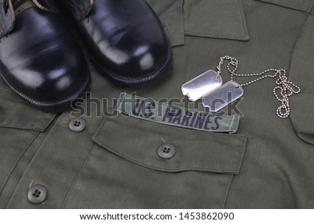 U.S. MARINES Tape with dog tags and boots on olive green uniform background