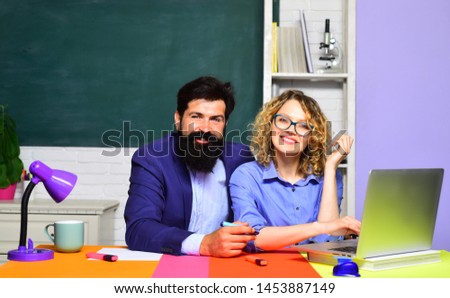 Funny young teacher with young student in classroom. Happy teachers couple in classroom. University students at college. Girl student with bearded teacher in auditorium. Learning, education concept.