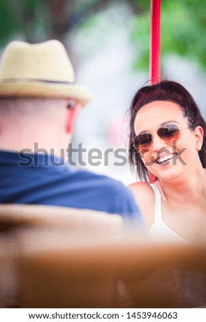 Lifestyle photography. A relaxed young dark haired woman outdoors with sunglasses