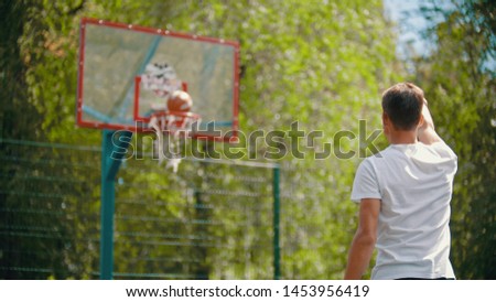A young man throwing the ball in the basketball hoop and it gets in the target