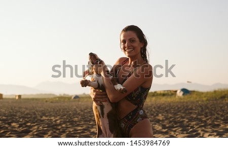 A beautiful young girl have fun with her dog on the beach