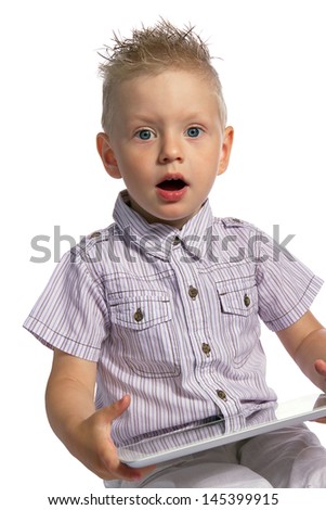 Surprised blond young boy with his mouth open, holding in his hands a tablet pc and looking at the camera isolated on white background