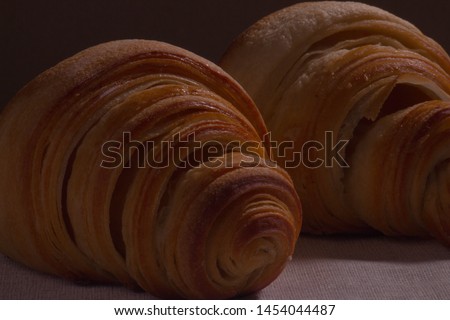 Two croissants one after another. Black background.