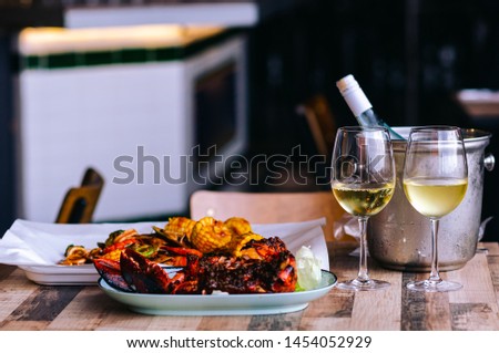 Two glasses of white wine on the table with a bottle in wine chiller bucket and seafood dish for a couple dining.