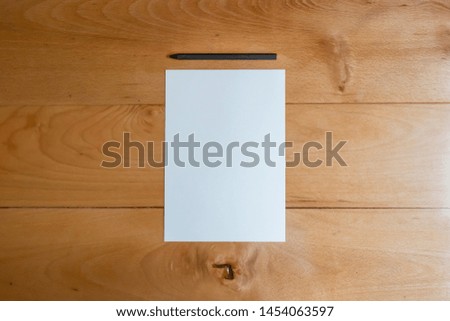 Modern pencil and white sheet of paper on bright wooden desk