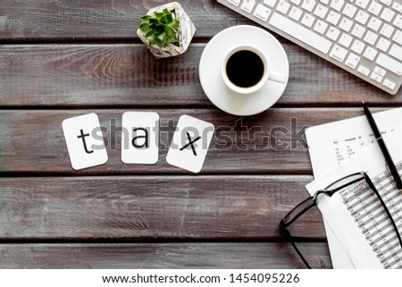 work desk with tax text, keyboard, coffee and accounting calculation on wooden background top view