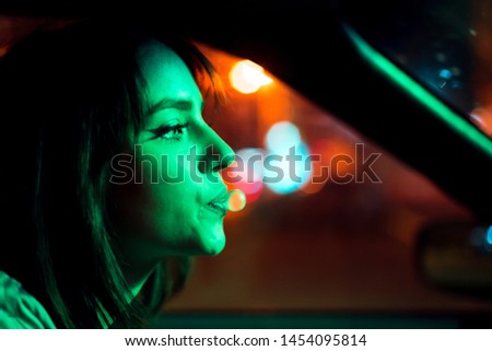 Cinematic night portrait of girl and neon lights in the car. Bubble gum.