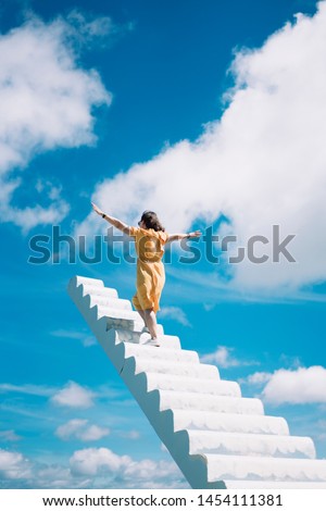 A girl standing on a white heavenly staircase extends into blue sky  Dalat, Vietnam. Royalty-Free Stock Photo #1454111381