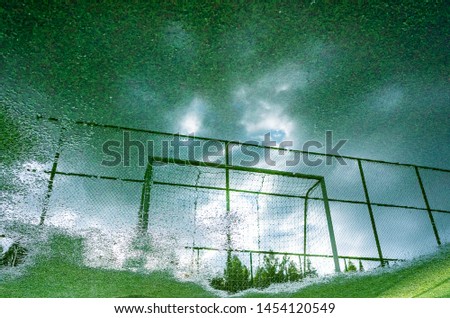 Reflection in a puddle in the stadium of a football goal on the background of a sky oblanny. Creative view of the stadium, inverted picture. Place for text.