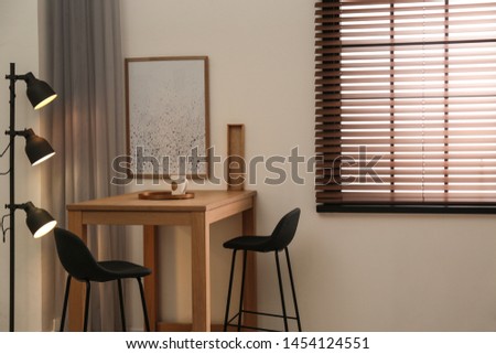 Modern room interior with table set, window blinds and stylish decor elements Royalty-Free Stock Photo #1454124551
