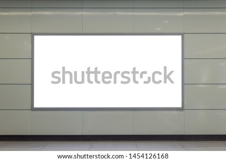 A clean, tidy subway station wall hangs a rectangular luminous blank billboard