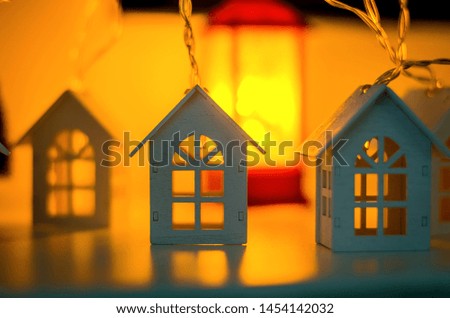 Magical Christmas decorative garland with lights, winter background with Silhouette of decorative houses Close-up of beautiful, bright and festive Christmas ornament. bokeh selective focus