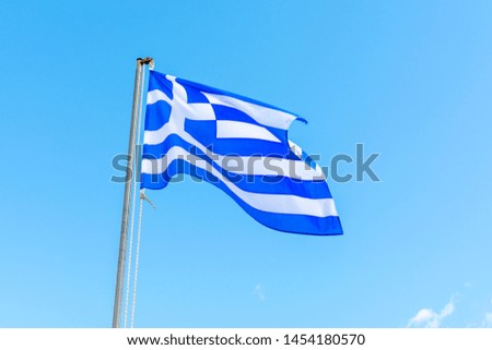 National symbol of Greece, blue-white greek flag on flagpole, sea water and blue sky, copy space