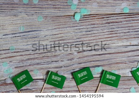 23 September, al-Yaom al-Watani, Day of proclamation of the Kingdom of Saudi Arabia. happy independence day concept of patriotism. mini flags with colorful confetti on wooden background