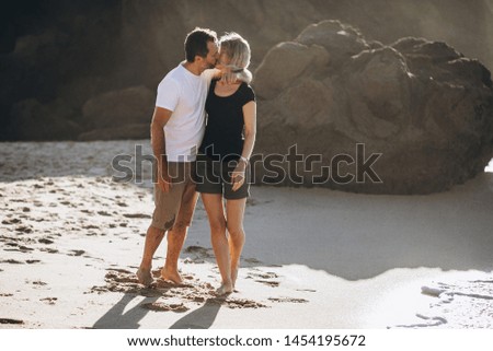 Couple kissing on the beach with a beautiful sunset in background, man hugging the woman