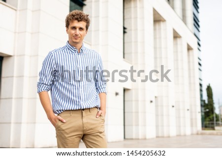 smart casual man standing in front of an important building inspiring confidence and success smiling to camera
