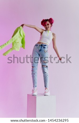 a woman with pink hair sits on a cube in her jeans jeans green