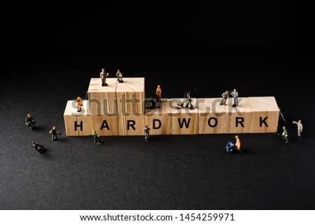 Concept shot for Hardwork. Miniature Builder Figures around Wooden Blocks with “HARDWORK” wordings