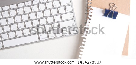 blank torn note paper on white wooden table with computer keyboard.top view,flat lay