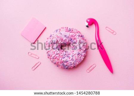 Pink doughnut and Flamingo pen on a pink background. Top view Flat lay