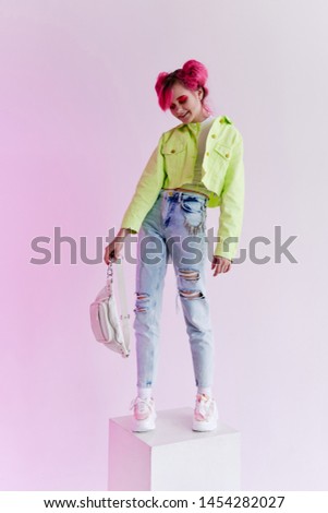 woman with pink hair in hand bag stands on the cube