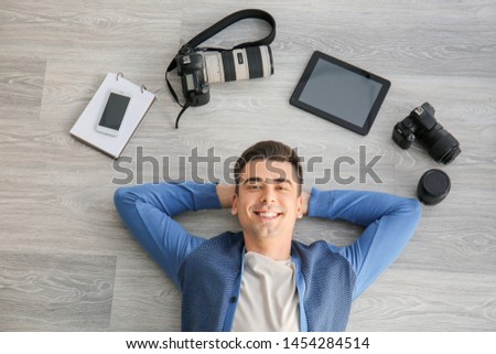 Male photographer with different devices lying on floor