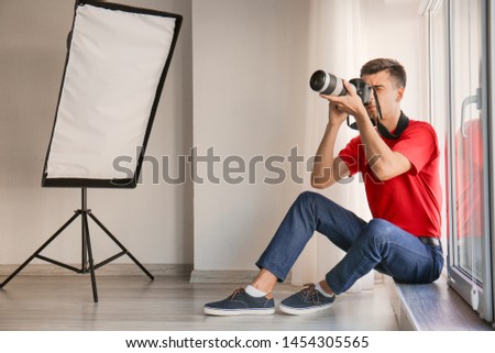 Male photographer sitting on window sill in studio