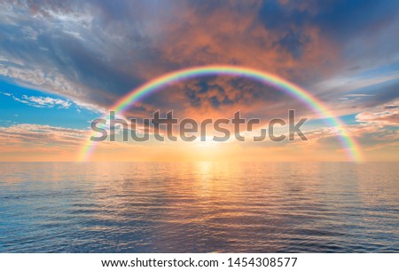 Storm on the calm sea with amazing rainbow, sunset in the background