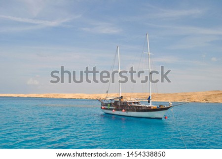 Ship against the blue sea and golden sand.  Ship in the open red Sea. Egypt.  Royalty-Free Stock Photo #1454338850