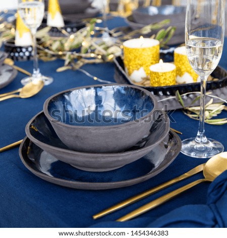 Festive Winter Holiday Table Scape Decor in Blue and Gold colors. Navy Blue Table Linens and Gold Cutlery.