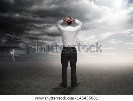 Businessman standing in a desert during a stormy weather